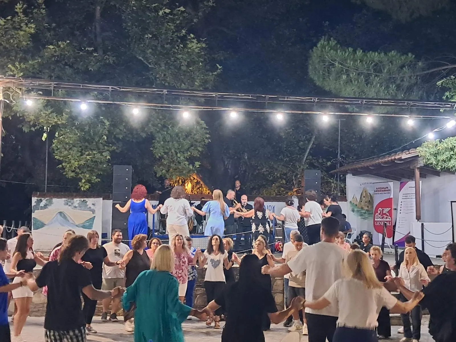 Μεγάλος κύκλος χορευτών στην πλατεία με την ορχήστρα στο βάθος