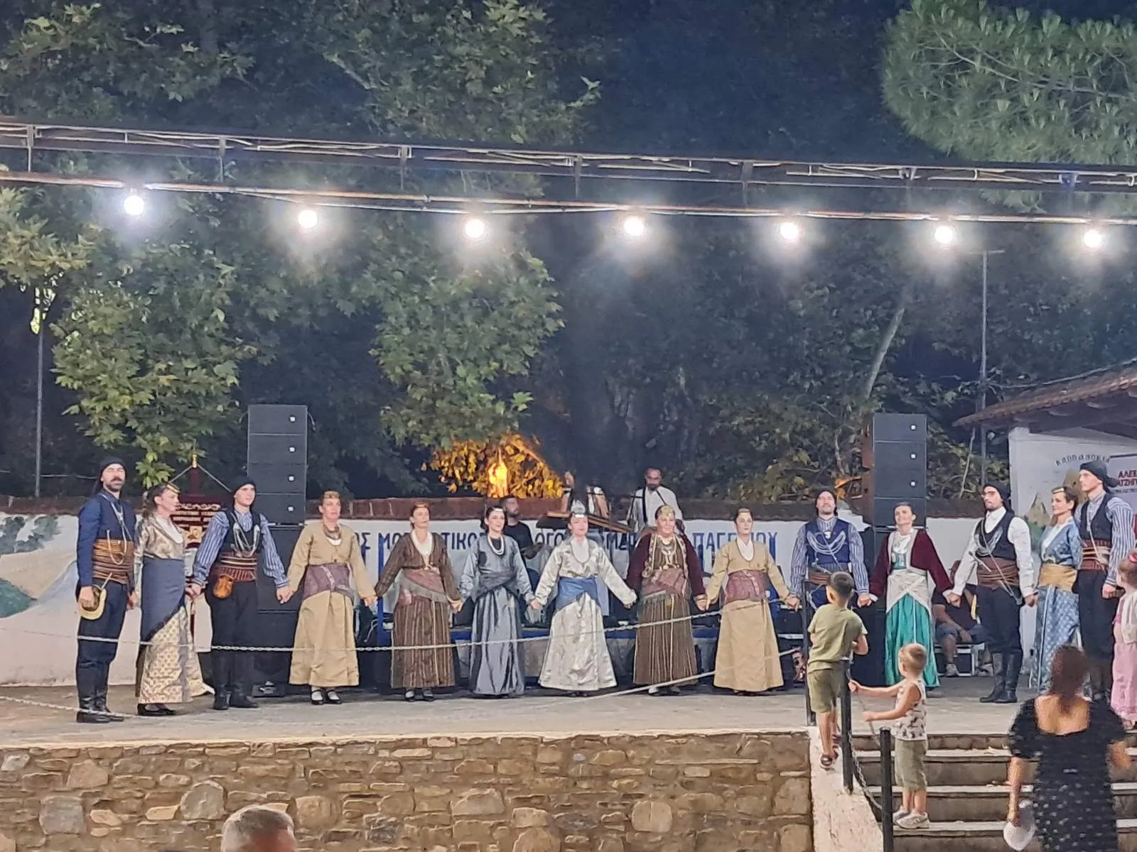 Χορευτικά συγκροτήματα με παραδοσιακές στολές σε παράταξη επί σκηνής